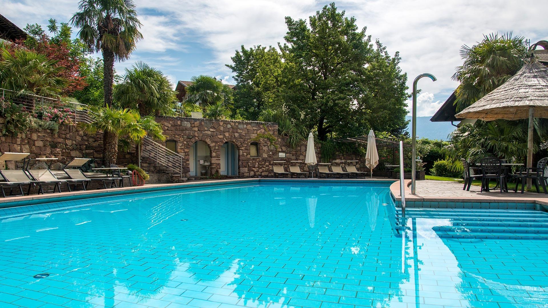 Pool mit Sonnenschirme und  Liegestühle von Grün umgeben Hotel Lichtenberg in Algund